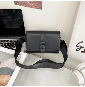 Modern black box crossbody bag with nylon strap and buckle on a minimalist desk setup
