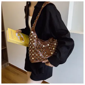 Detailed close-up of brown leather underarm bag featuring silver metal eyelet rivets