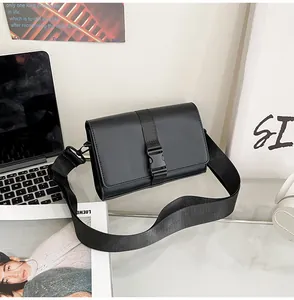 Detail of minimalist black messenger bag with plastic buckle closure on glass table