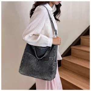 Detail of large dark grey washed denim tote bag with front pocket and adjustable strap