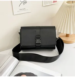 Detail of the black rectangular crossbody bag featuring a matte buckle and wide strap