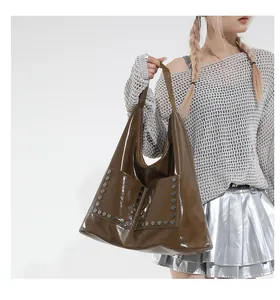 Detail of vintage brown tote bag with glossy finish and rivet-decorated pockets