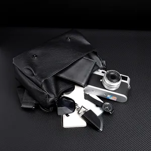 Close-up of black pebble leather messenger bag with magnetic buckles and interior wallet