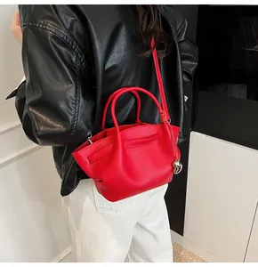Detail of red pebbled leather tote with silver heart charm and knotted shoulder strap