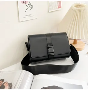 Close-up of minimalist black box shoulder bag with matte finish and buckle detail