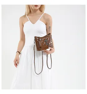 Detail of brown quilted crossbody bag with punk cross and skull charms and chain strap