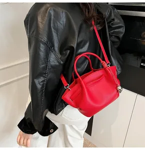 Close-up of red lychee grain leather tote bag with silver charm and crossbody strap