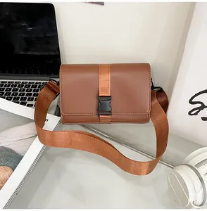 Close-up of brown rectangular crossbody bag with nylon strap and plastic buckle detail