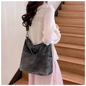 Detail of grey washed denim tote bag showing leather logo patch and front pockets