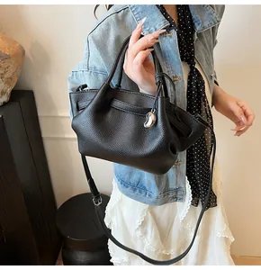 Close-up of black litchi grain leather tote with silver pendant and adjustable strap