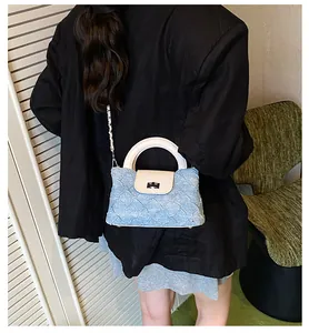 Detail der gesteppten Denim-Beuteltasche in Blau mit beigem Lederbesatz und Silberkette