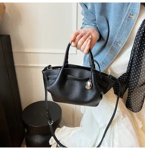 Detail of black lychee texture leather tote bag with silver heart charm on white background