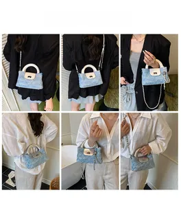 Detail der hellblauen Denim-Stepptasche mit Metallkette und rundem Griff im Fokus