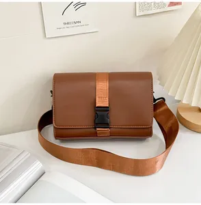 Brown leather square box bag with nylon strap shown in a cozy minimalist home setting