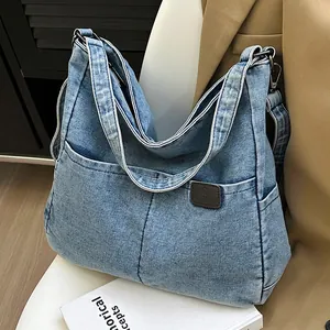 Light blue denim tote bag with leather logo detail and adjustable shoulder strap