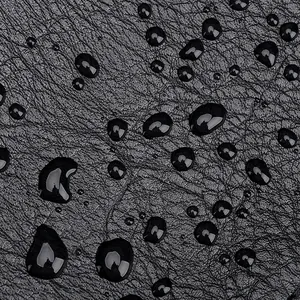 Macro shot of waterproof black pebble-grain PU leather surface with water droplets