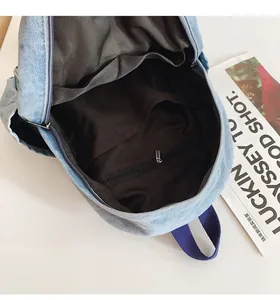Détail de l'intérieur du sac à dos en denim bleu montrant les poches et la doublure brune