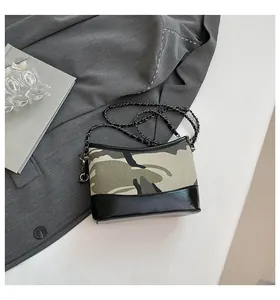 Detailed close-up of camouflage canvas and black glossy leather patchwork on chain bag