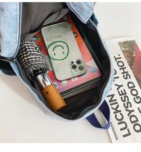Vue intérieure du sac à dos en jean montrant sa grande capacité pour tablette et parapluie