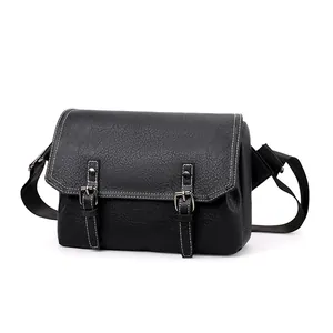Detail of black PU leather messenger bag showing lychee texture and white contrast stitching