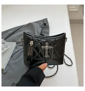 Detail of black quilted leather hobo bag with vintage silver cross and skull chain