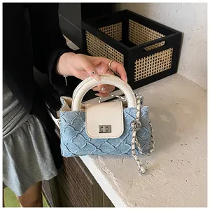 Detail der hellblauen gesteppten Denim-Mini-Eimertasche mit Ledergriff und Kettengurt