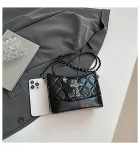 Close-up of black quilted chain bag featuring gothic cross and skull metal pendants