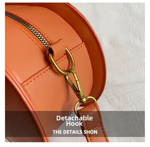 Close-up of detachable gold metal hook and fine leather texture on orange pumpkin bag