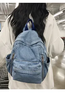 Sac à dos en toile denim bleue avec plusieurs fermetures éclair porté sur le dos