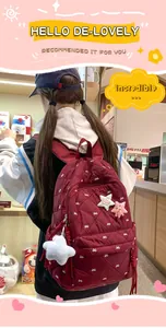 Detail of burgundy quilted backpack with bow embroidery and plush star charm accessory