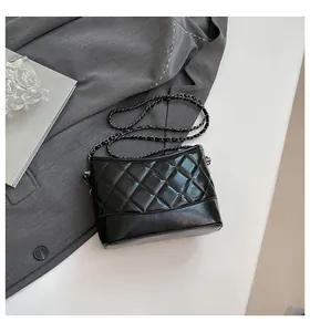 Detail of black quilted leather hobo bag with silver chain strap on grey fabric