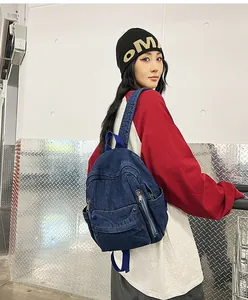 Détail du sac à dos en jean vintage avec poche à rabat avant et fermetures éclair