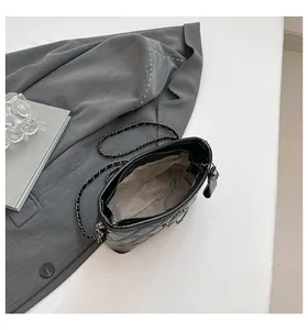 Close-up of quilted black leather hobo bag with woven chain strap and fabric lining