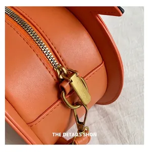 Detail view of smooth golden metal zipper on high-quality orange pumpkin bag leather