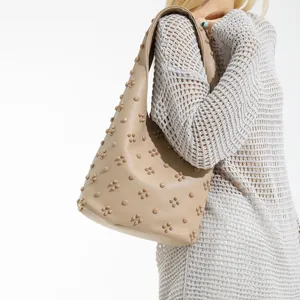 Vintage beige rivet shoulder bag with pebble grain texture shown on model in studio