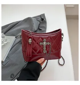 Detail of burgundy quilted leather bag with gothic cross and skull charms