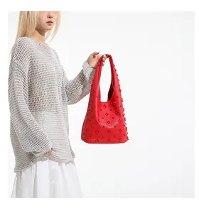 Detailed close-up of a red leather handbag with 3D floral rivet studs on the bag exterior
