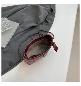 Close-up of quilted burgundy leather texture and woven chain strap on a chic hobo bag