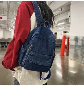 Vue détaillée du sac à dos en jean bleu foncé montrant le tissu et les sangles en nylon