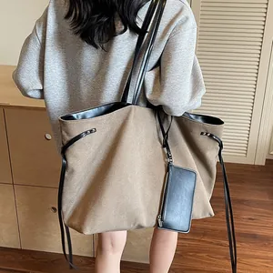 Large khaki canvas tote bag with black leather straps shown on shoulder for daily use
