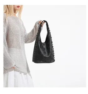 Detail of black pebbled leather shoulder bag with 3D floral rivet studs and handle