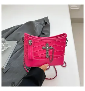 Detail of fuchsia crocodile texture bag with gothic metal cross and skull charm