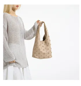 Detail of beige hobo bag with textured pebble leather and decorative studs on shoulder