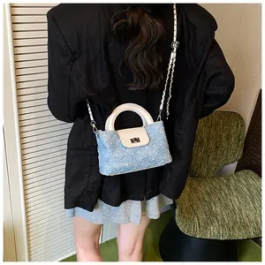 Detailansicht der blauen Stepptasche mit weißer Lederklappe und silbernem Kettenriemen