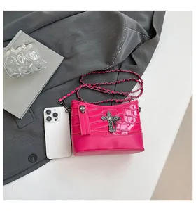 Detail of flamingo pink crossbody bag with crocodile texture and punk skull chain accent