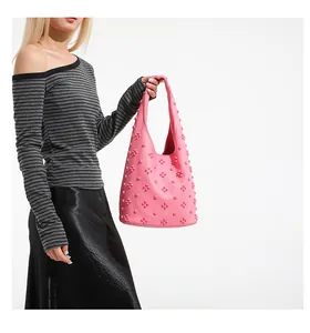 Detail of pink hobo bag featuring 3D floral rivet decorations and lychee grain leather