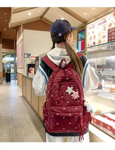 Detail of dark red quilted backpack with embroidered bows and cute star plush charms