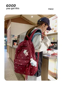 Deep red quilted backpack with white bow patterns and colorful star charms for casual use