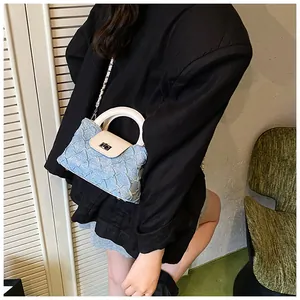 Detailansicht der blauen Denim-Beuteltasche mit weißem Ledergriff und silbernem Verschluss
