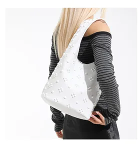 Detail of 3D floral rivets on the white minimalist leather shoulder bag worn by a model